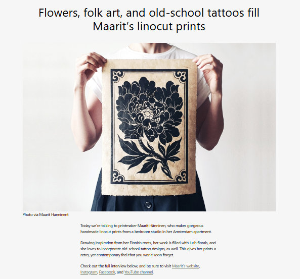 Person holding a linocut print with a floral design against a white background