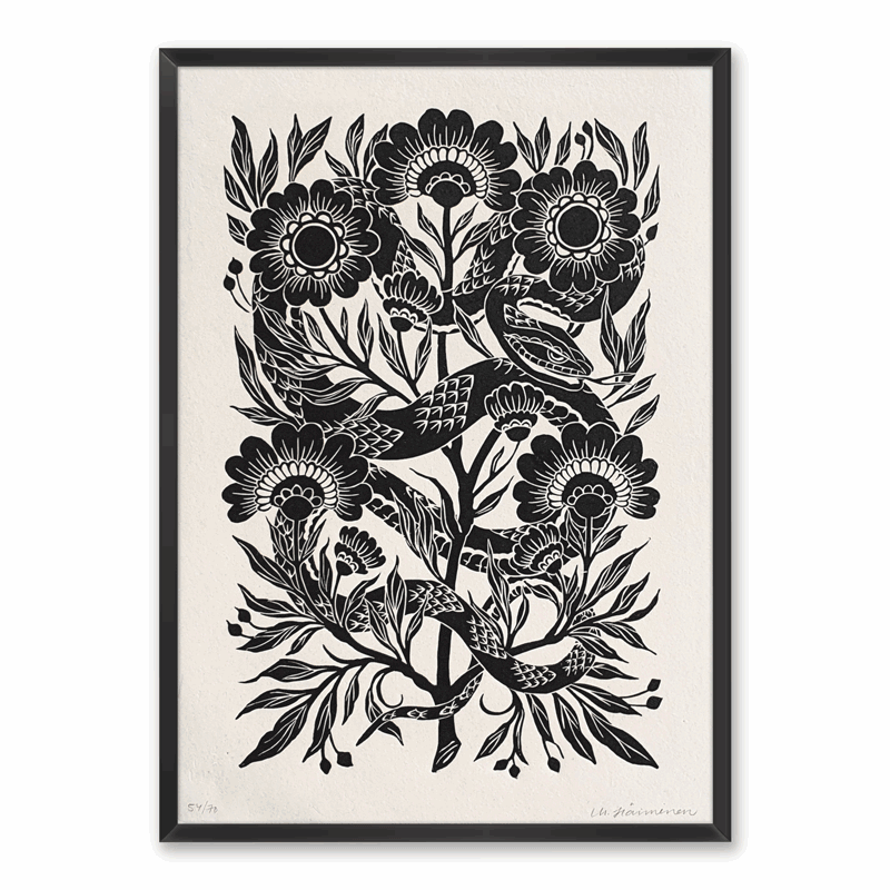 Linocut print of a snake surrounded by folk art style flowers, framed on a white wall