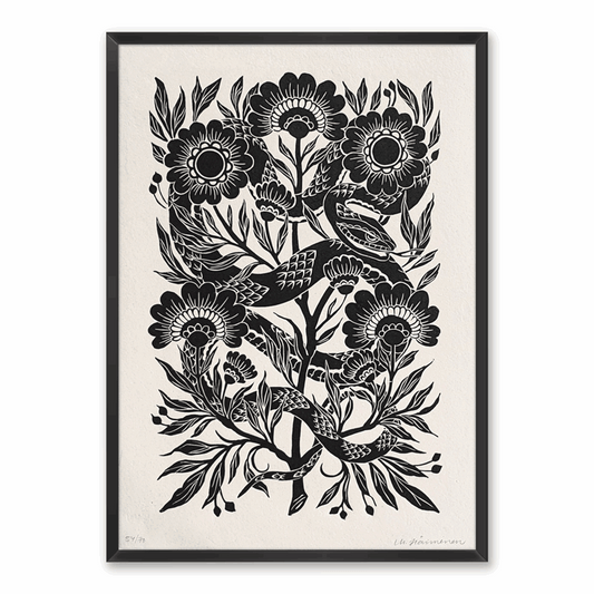 Linocut print of a snake surrounded by folk art style flowers, framed on a white wall