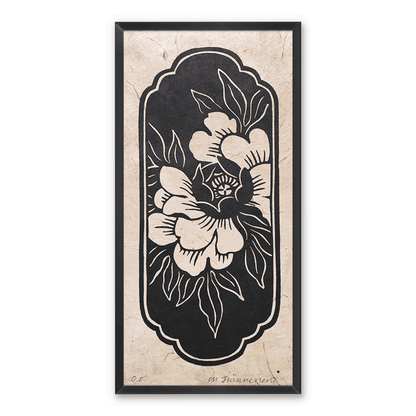 Linocut print of a peony flower with an ornate border, framed on a white wall