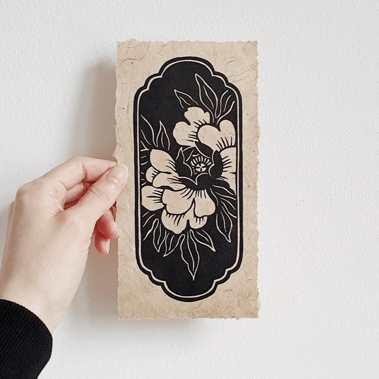 Woman holding a small floral linocut print against white background