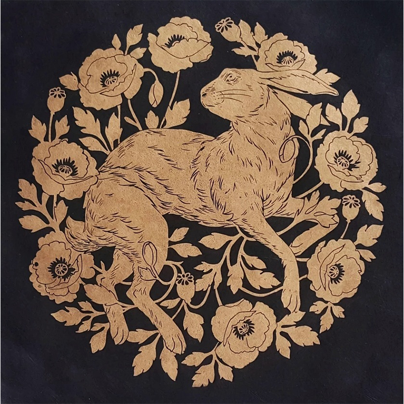 Linocut print of a golden hare and poppies on black paper