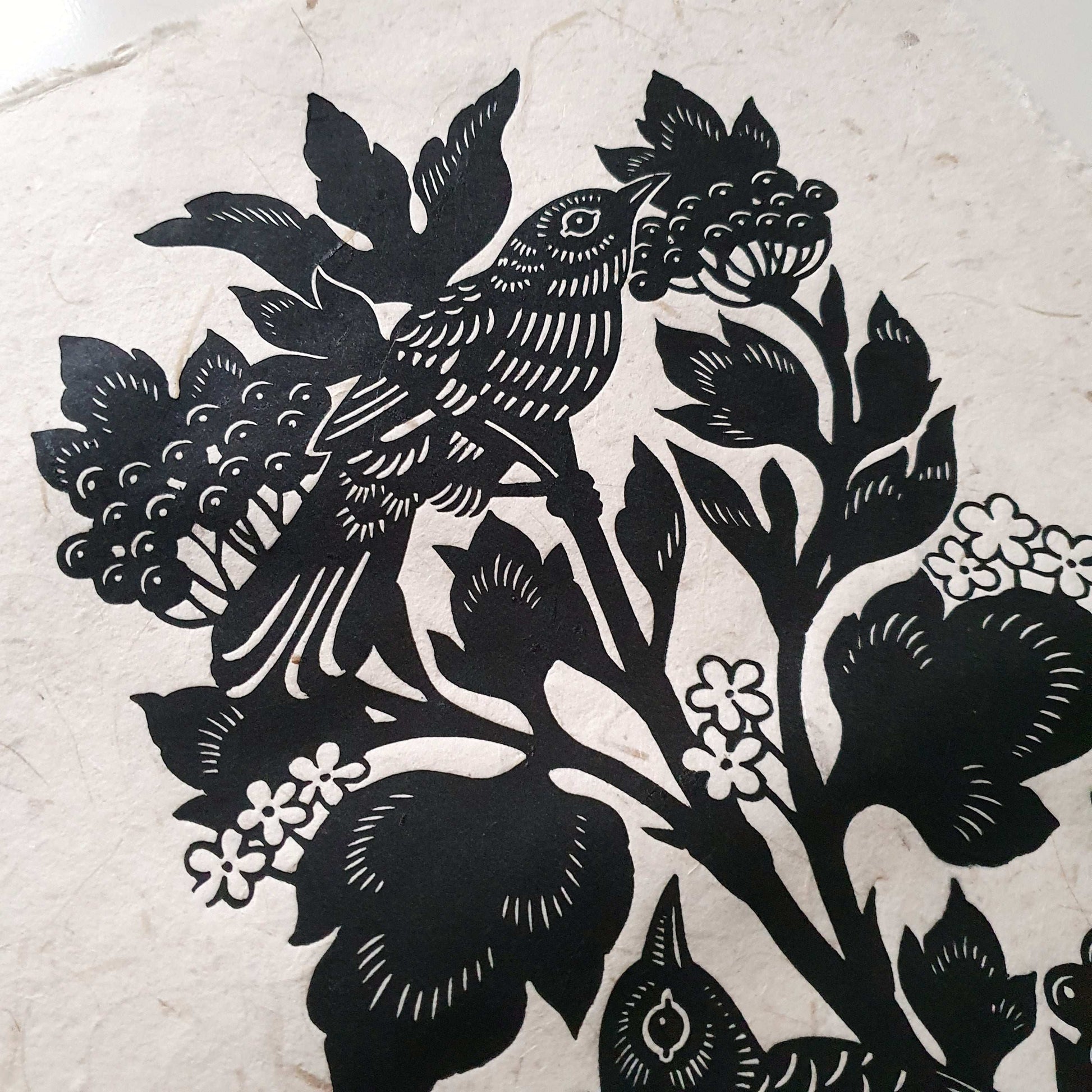 Detail of a handmade art print with a bird in a berry bush