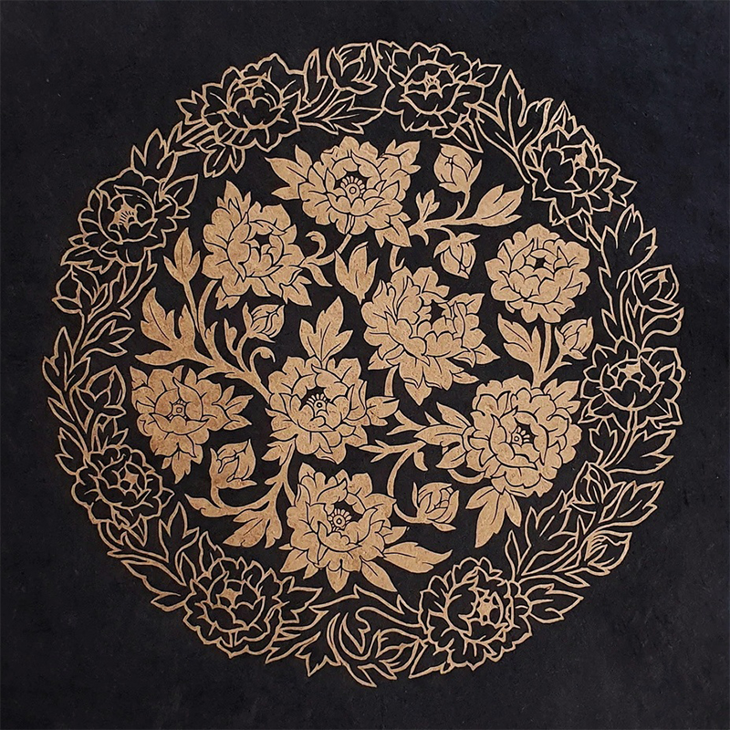 Linocut print of a circular floral pattern in gold and black 