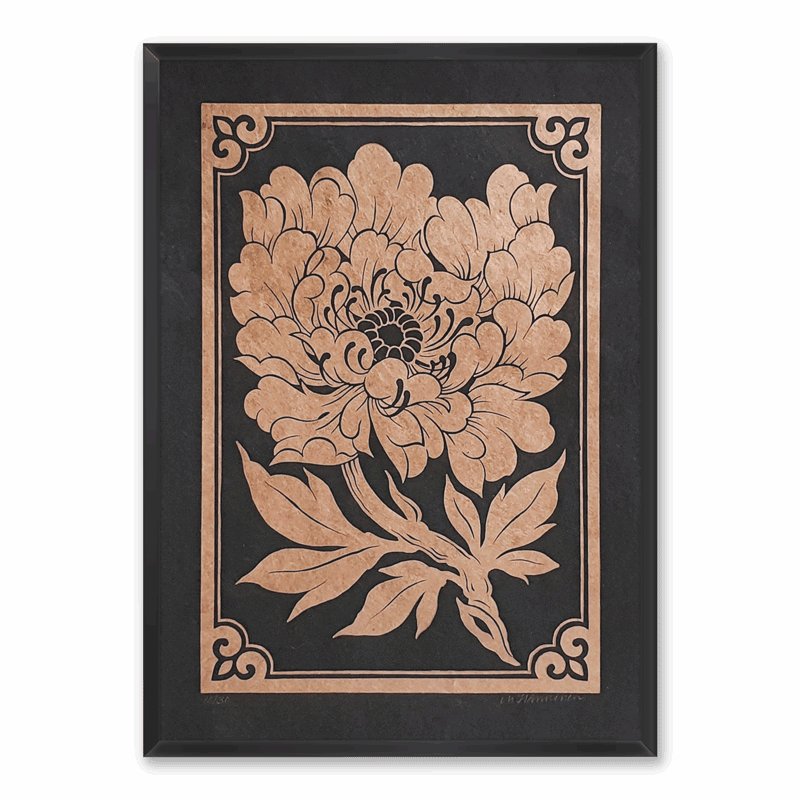 A framed linocut print of a golden peony on black paper