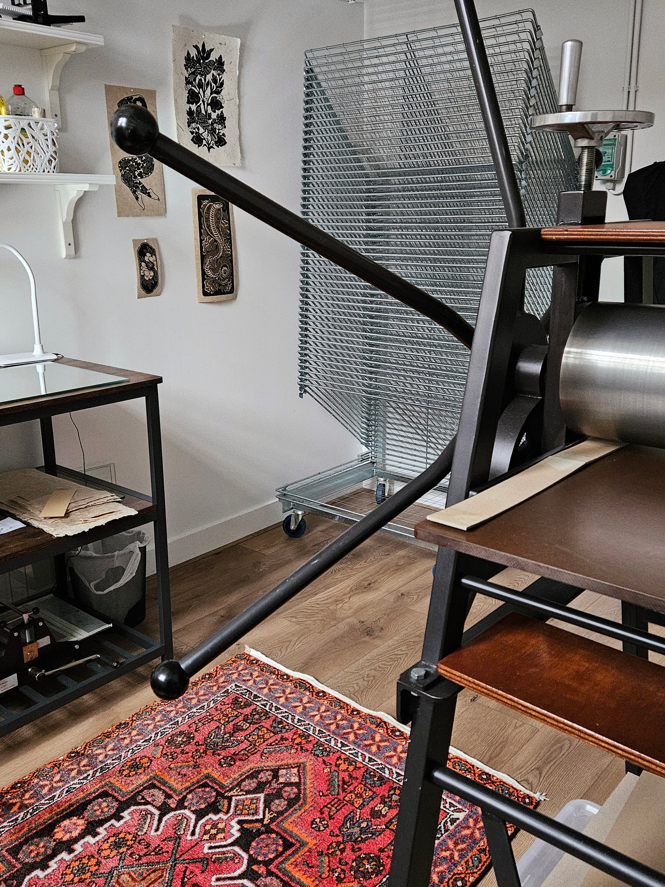 Printmaker's work space with an etching press and a print drying rack