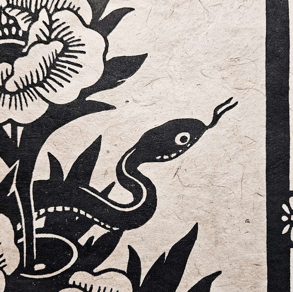 Detail of a woodcut print of a snake and flowers