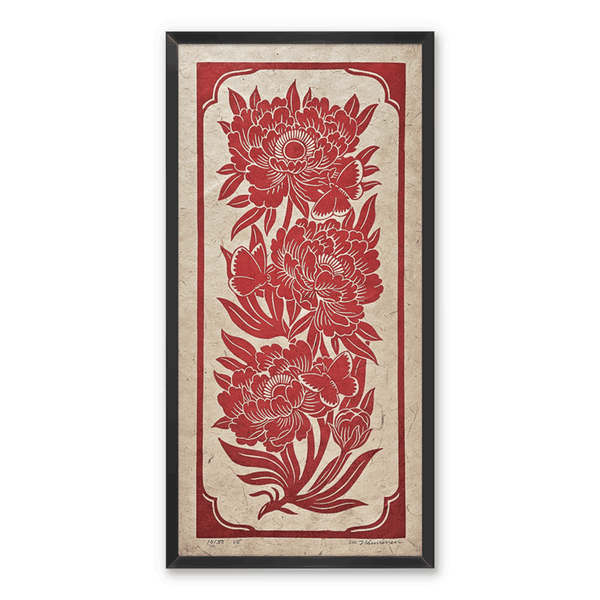 A linocut print of red peony flowers and butterflies, framed on a white wall