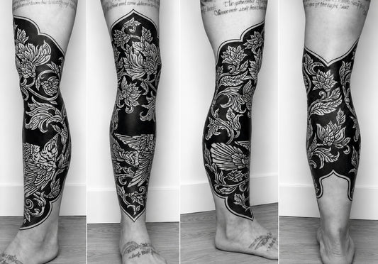 Black and white floral tattoo on a person's leg against a plain background