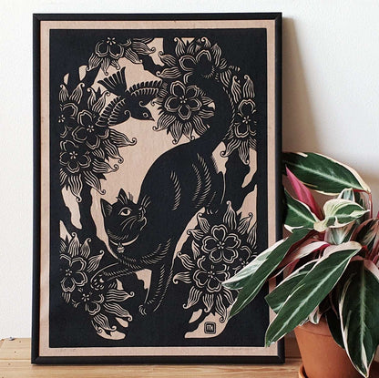 Framed cat linocut print next to a houseplant