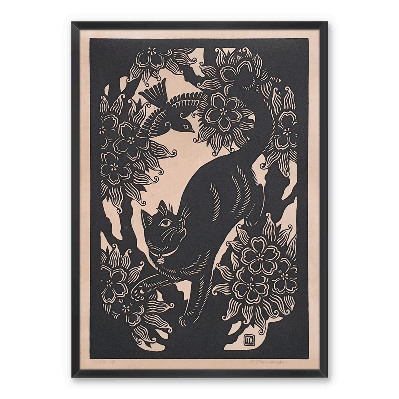 A framed linocut print of a black cat and a blackbird in a blossoming cherry tree