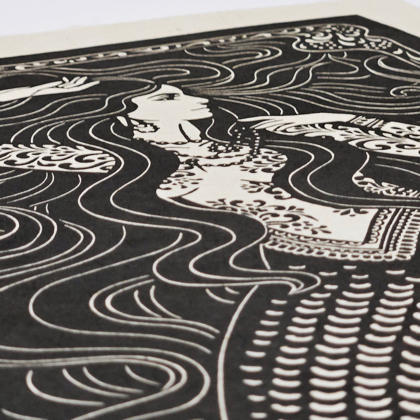 Black and white illustration of a mermaid with flowing hair and patterns in the background