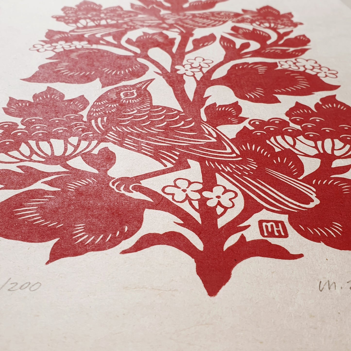 Detail of a red and white linocut print of a bird